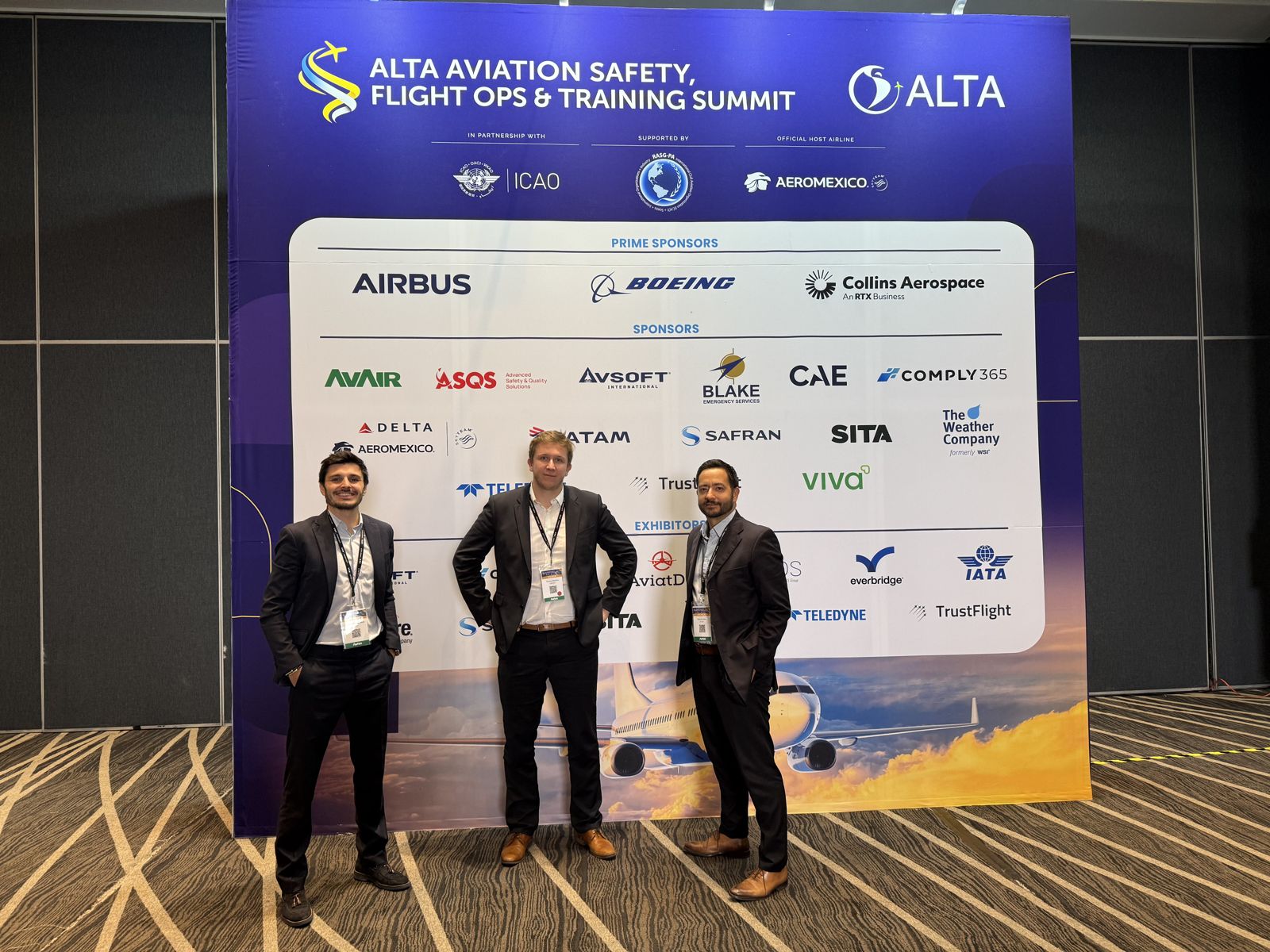 Three members of the Hinfact team in front of the ALTA Aviation Safety, Flight Ops & Training Summit backdrop.